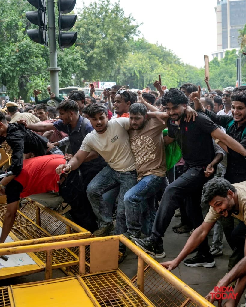 Protesters pushing against yellow police barricades in Delhi